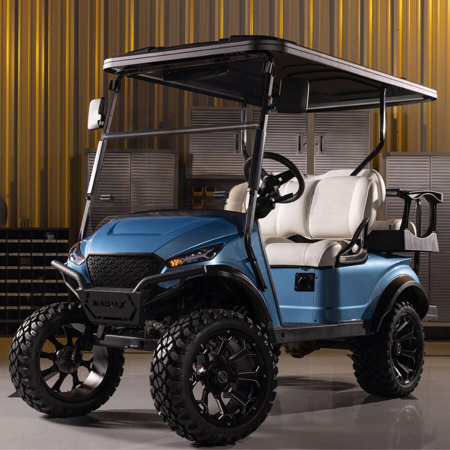 Blue golf cart with black wheels and off-road tires, parked inside a garage.