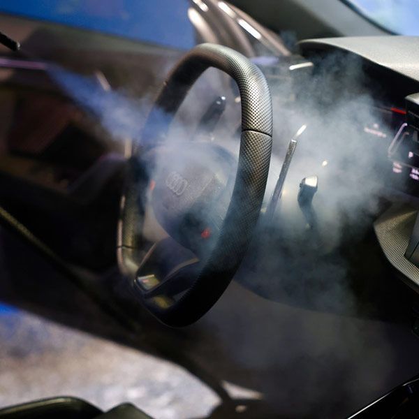 Steering wheel and dashboard of a car being steam cleaned
