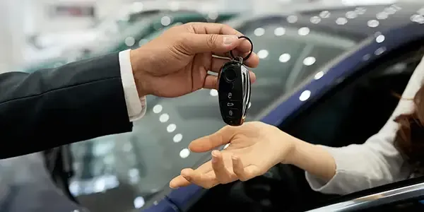 Handing car keys to a customer at a dealership showroom