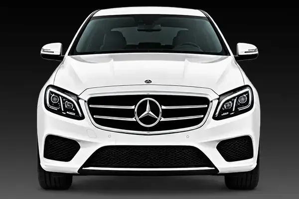 Front view of a white Mercedes-Benz sedan on a dark background