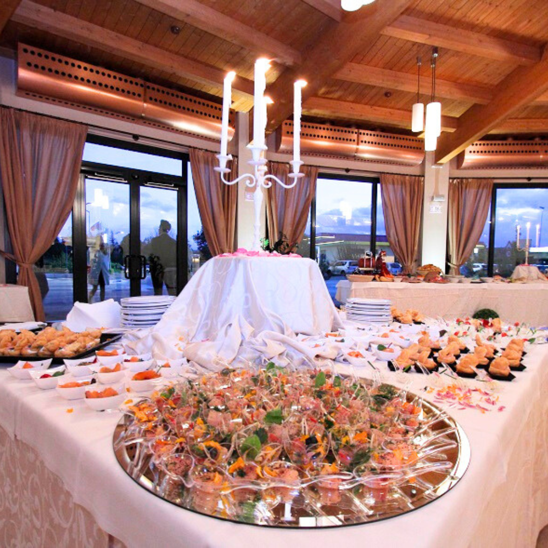 Tavolo da buffet con vari antipasti, candele accese e porte aperte sulla vista esterna.