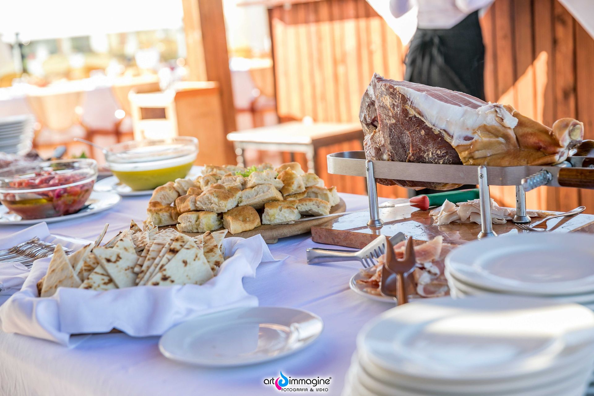 Tavolo da buffet con pane, salumi e vari antipasti.