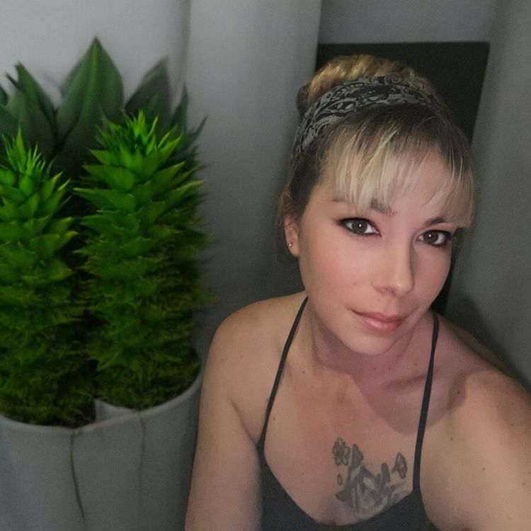 A woman with a tattoo on her chest is taking a selfie