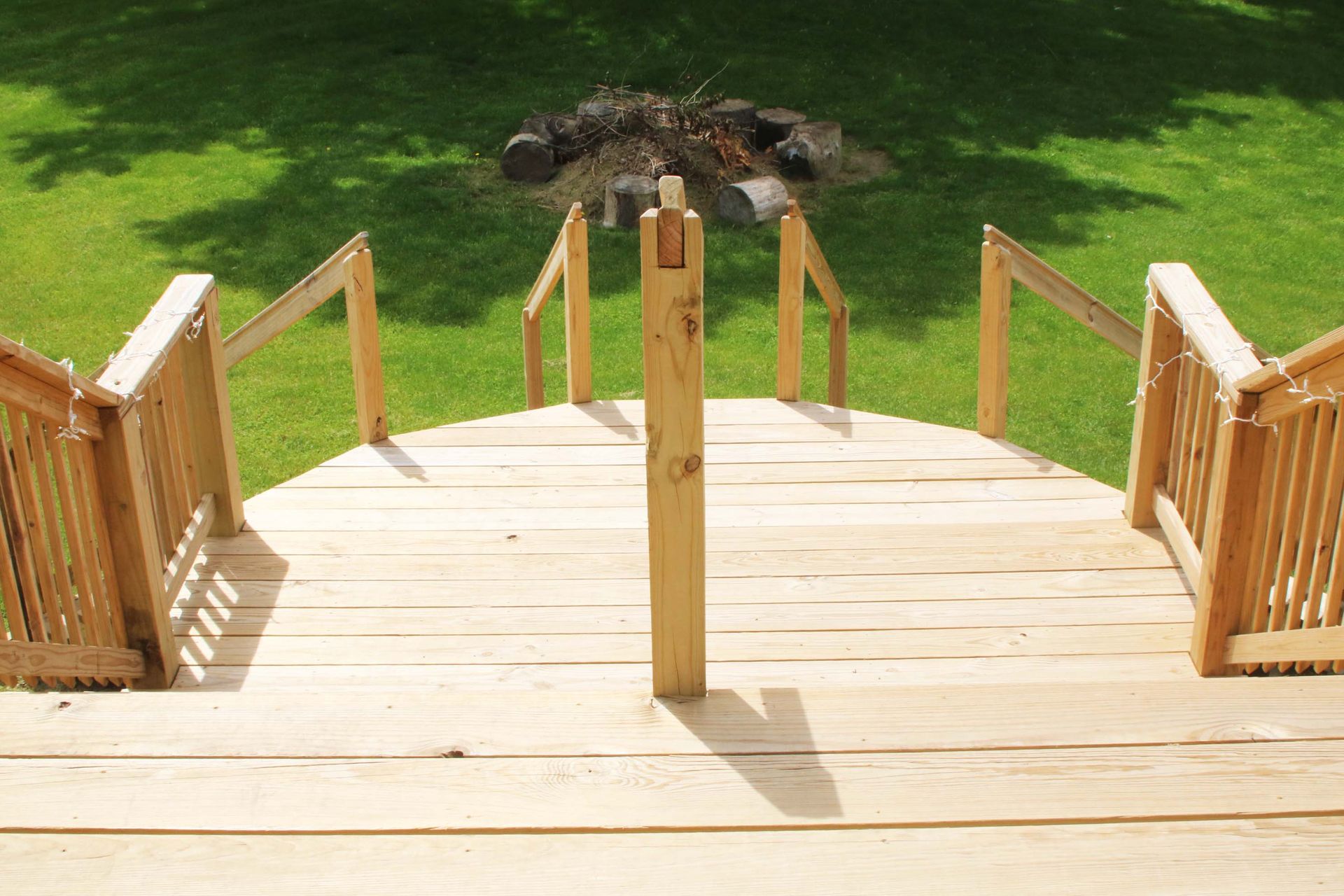 Wooden deck with steps leading to a green lawn. A fire pit is visible in the background.