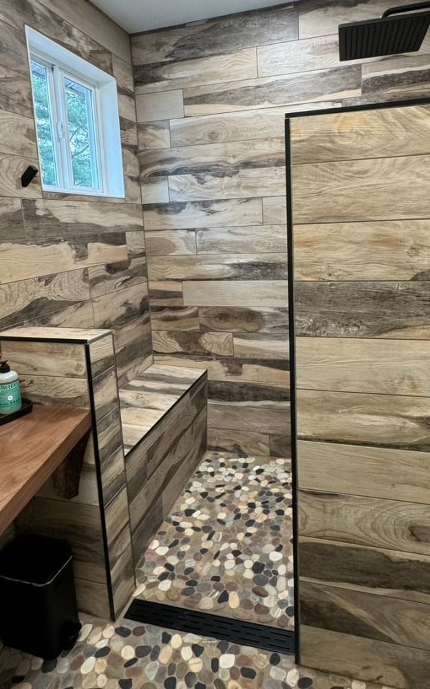 A bathroom with a walk in shower and a bench.