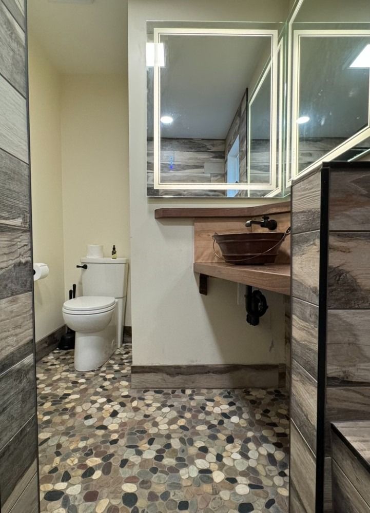 A bathroom with a toilet , sink and mirror.