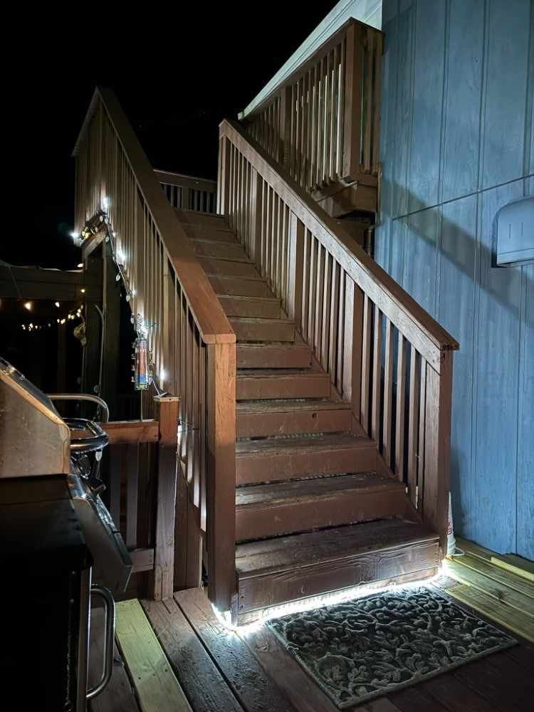 A wooden deck with stairs and lights on it at night.