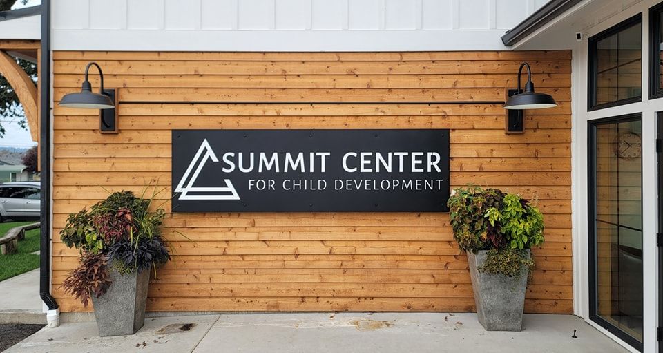 Summit Center for Child Development sign on a wood-paneled building entrance with potted plants