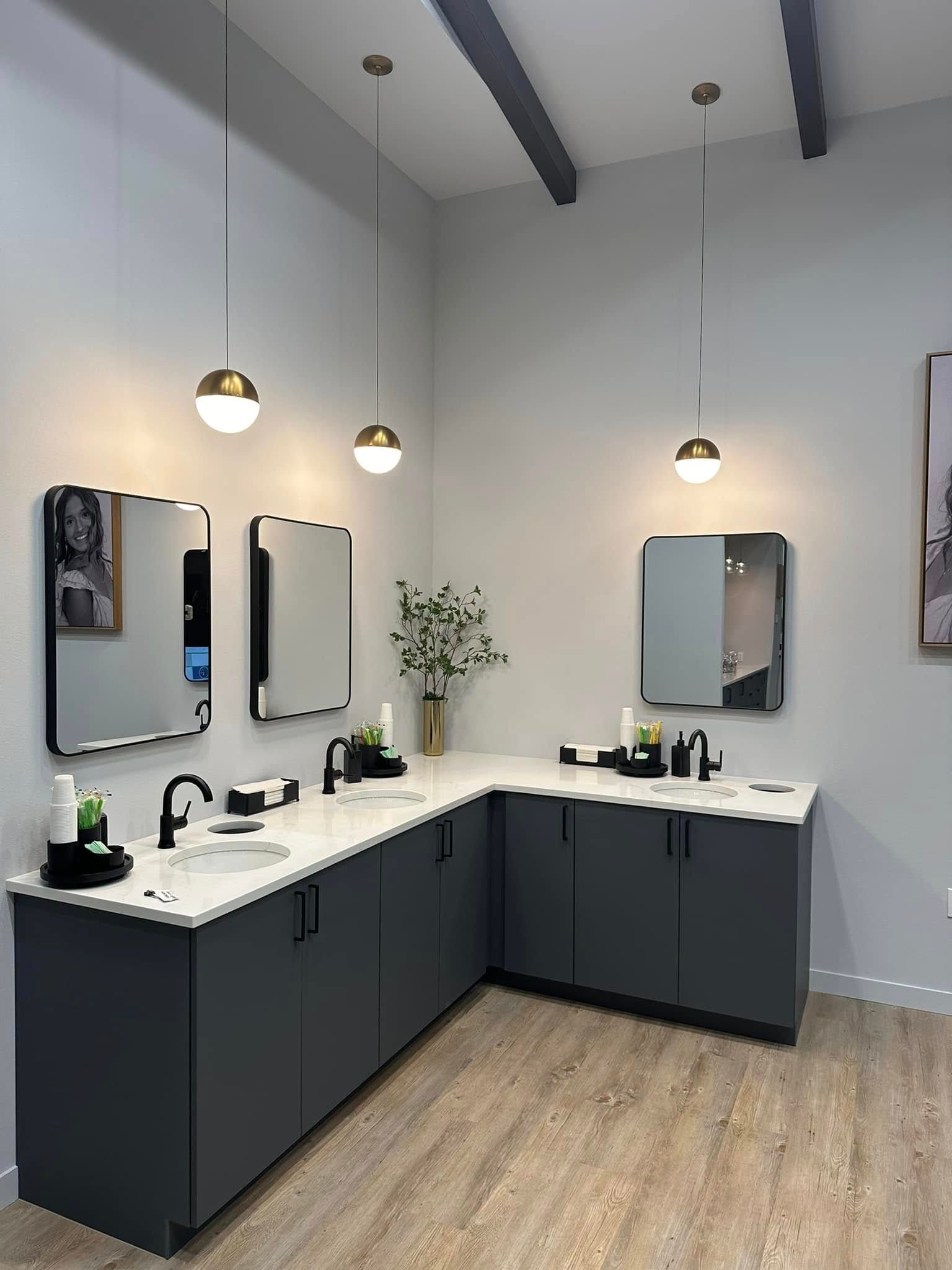 Modern salon with two styling stations, black cabinets, white countertops, mirrors, and pendant lights