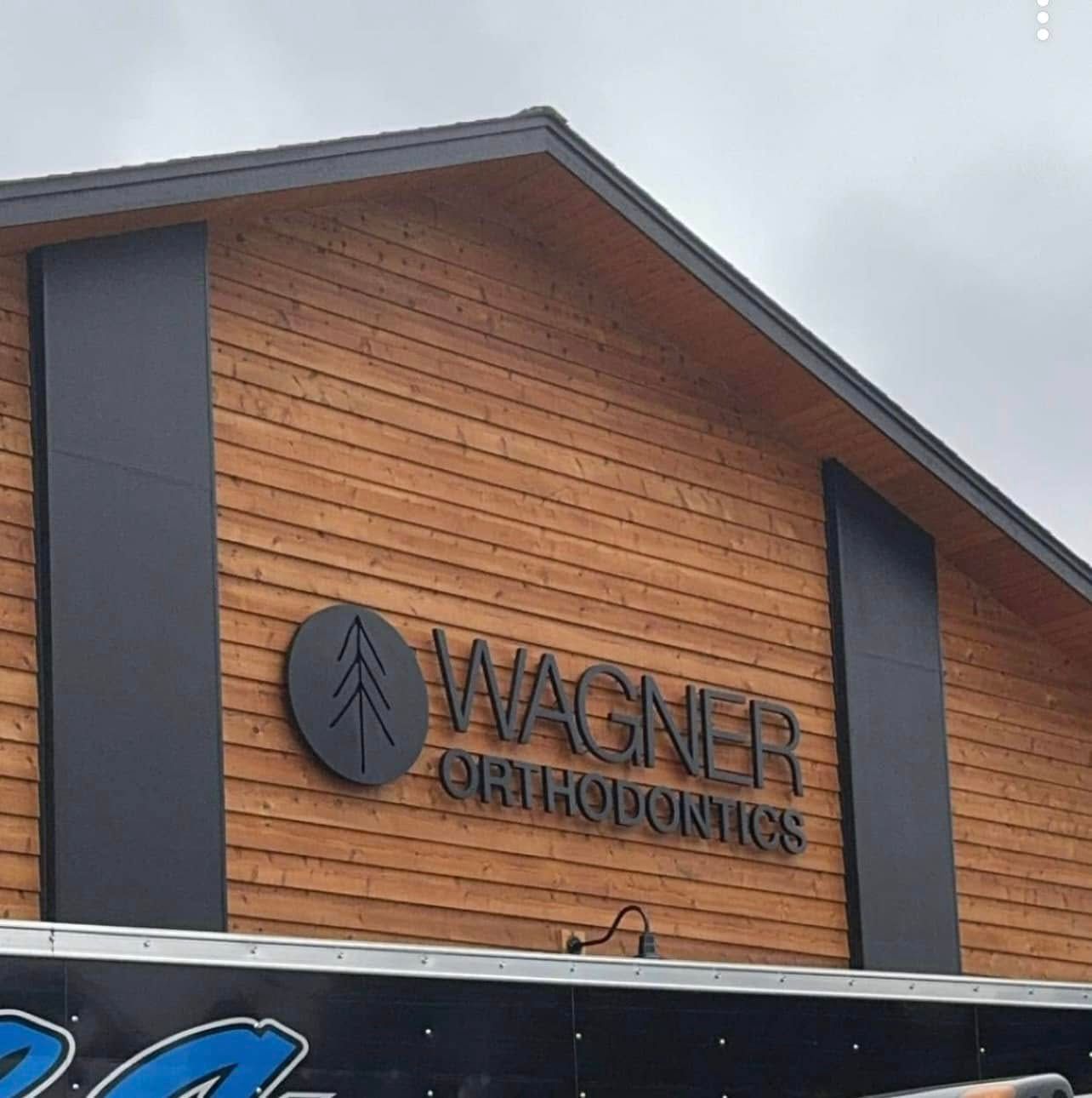 Wagner Orthodontics sign on a wood-paneled building exterior with dark trim under an overcast sky