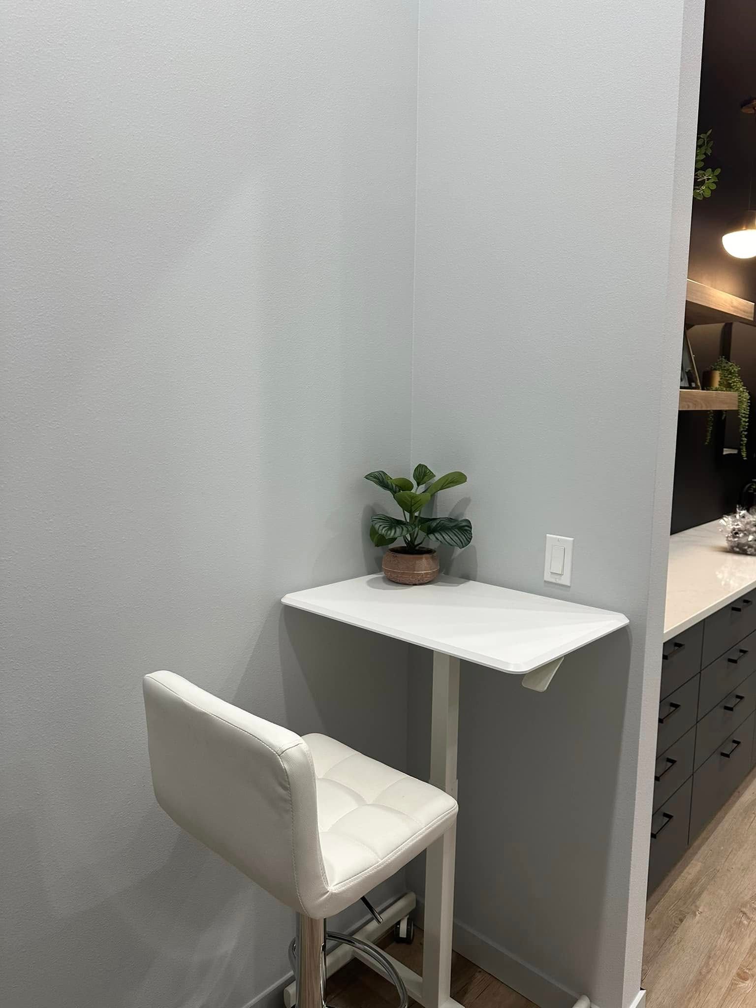 Small white desk with potted plant and white chair in a narrow corner alcove
