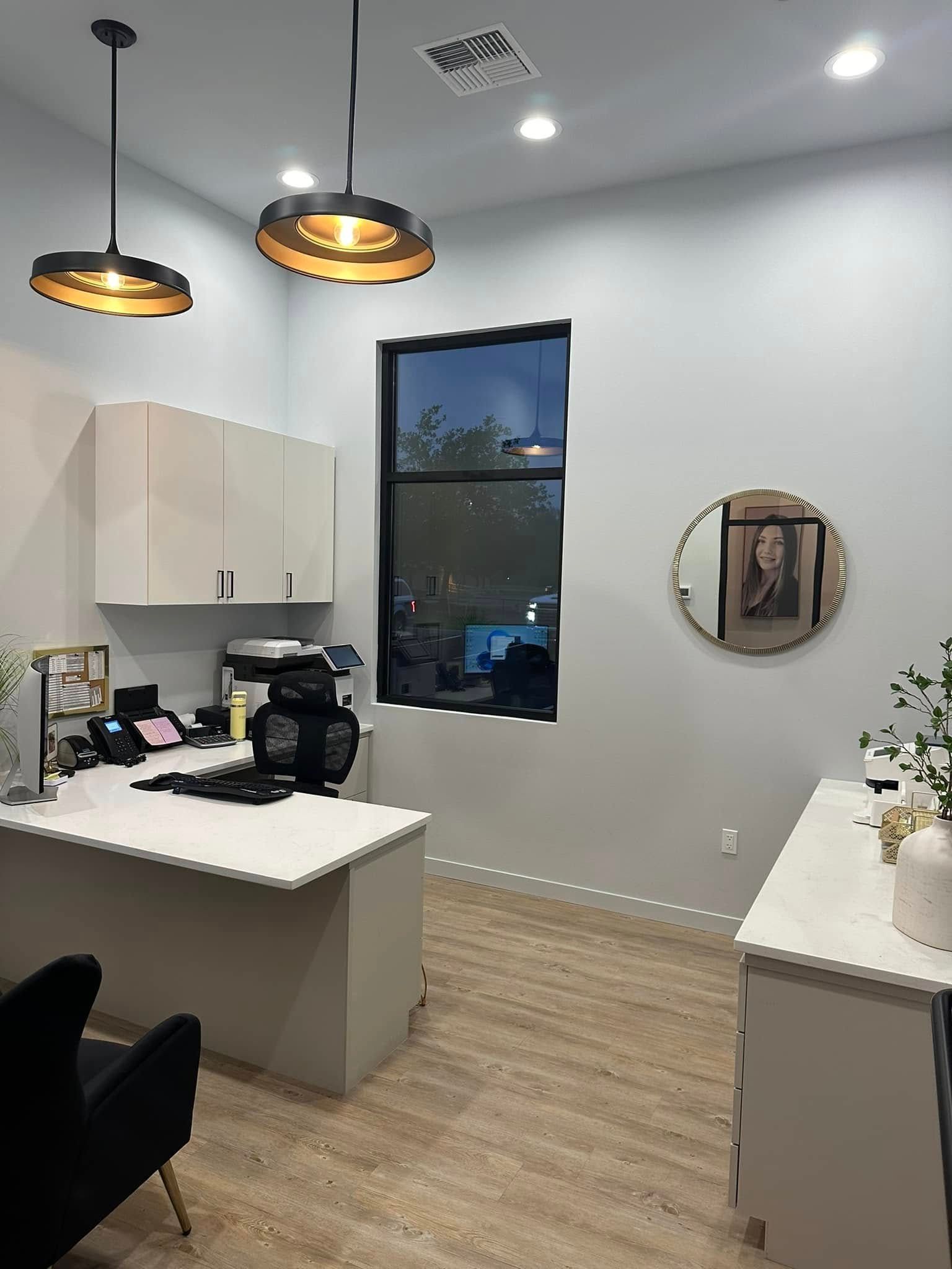 Modern kitchen with white cabinets, marble island, black window, pendant lights, and wood flooring