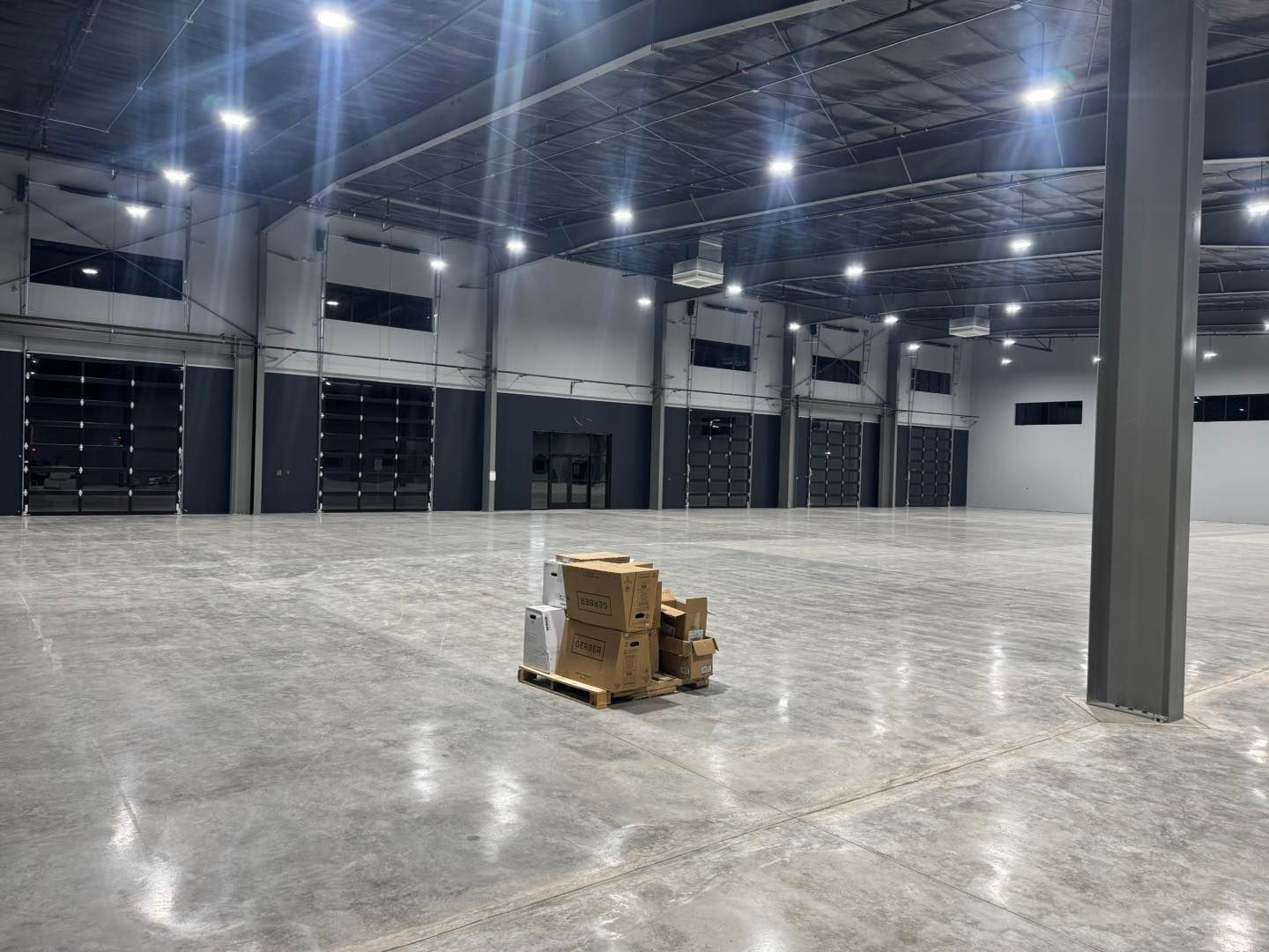 Empty warehouse with glossy concrete floor and a small stack of boxes in the center