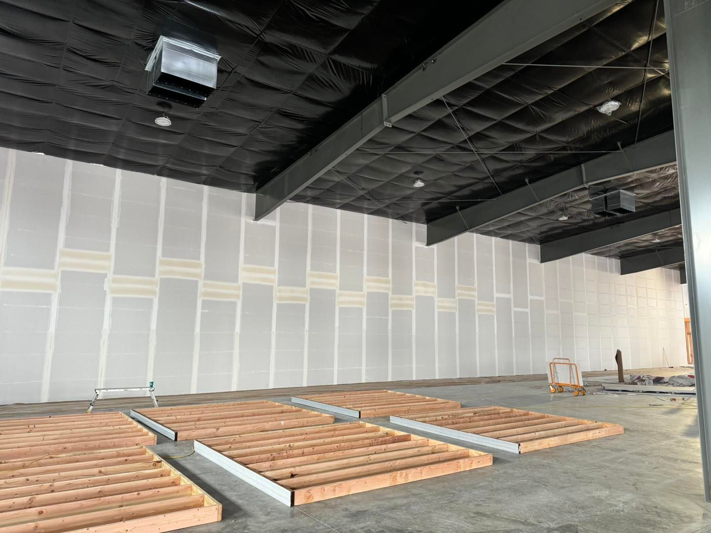 Empty interior under construction with framed floor sections and unfinished walls and ceiling