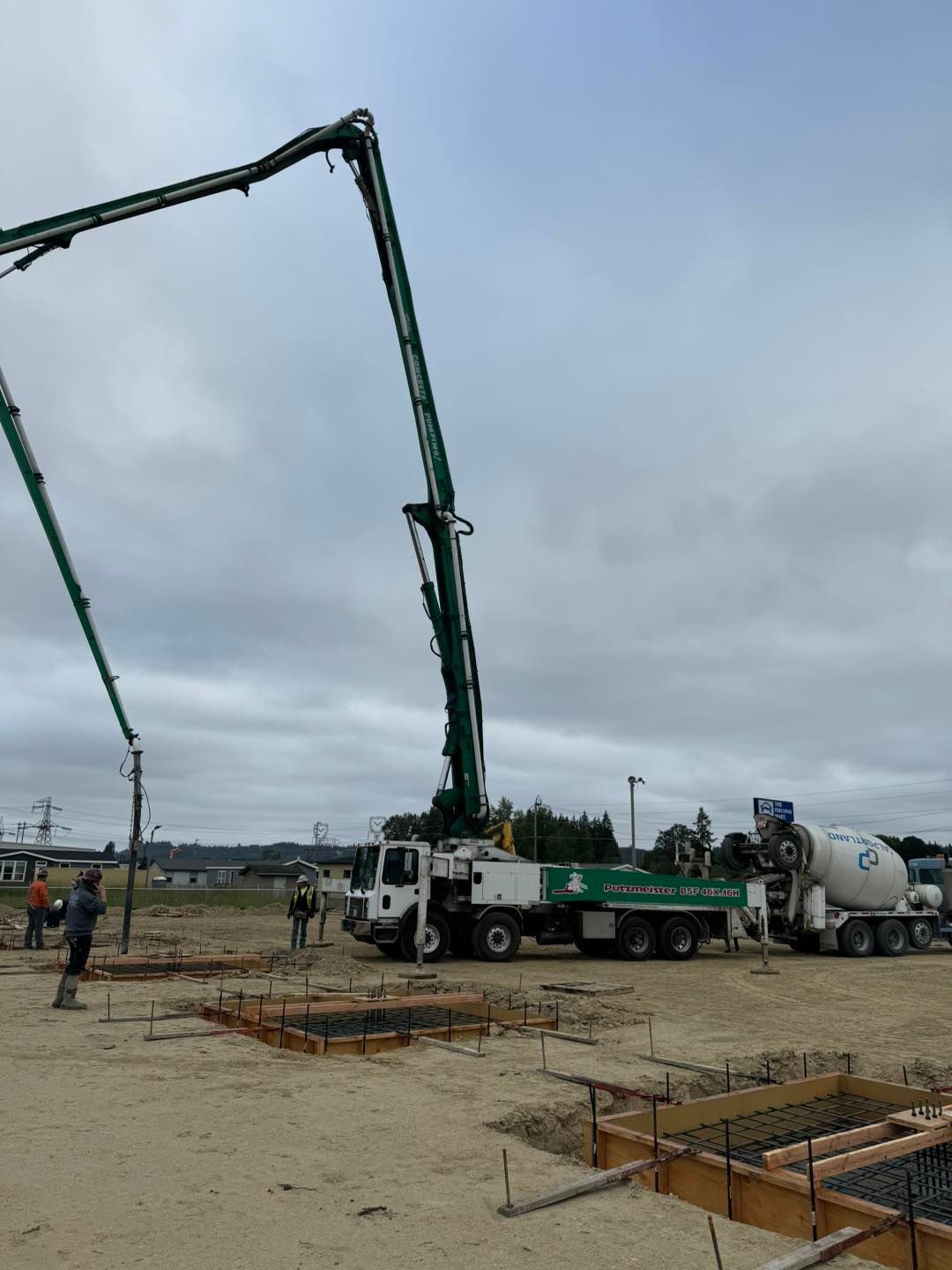 Concrete pump truck pouring at a construction site under a cloudy sky