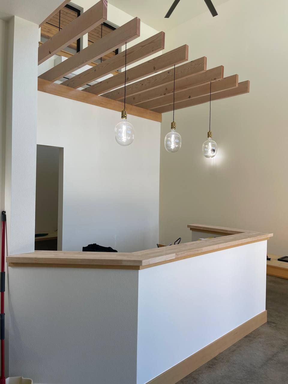 Modern reception desk with wood slatted ceiling and hanging pendant lights in a minimalist interior