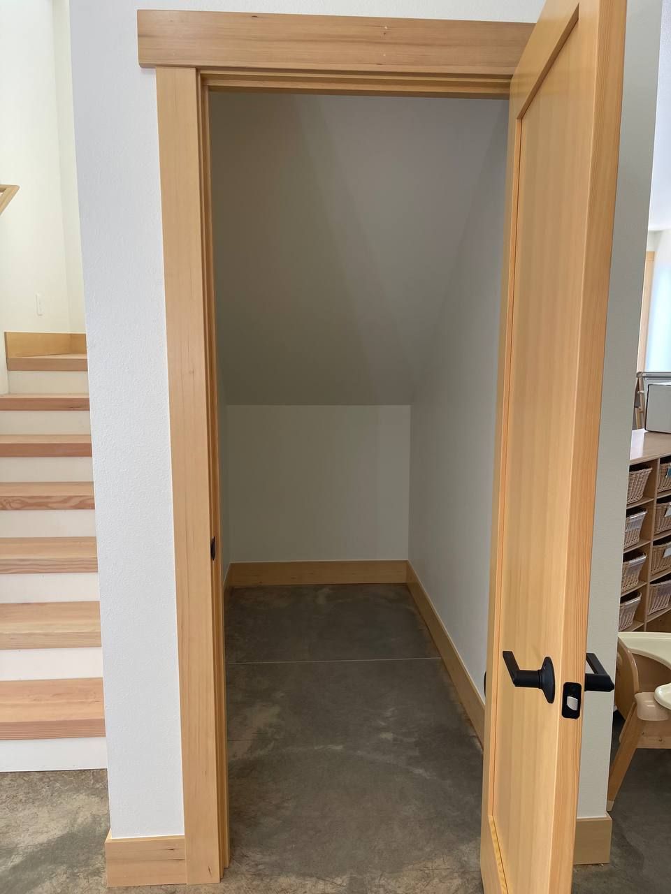Small open wooden doorway leading to a narrow unfinished alcove or storage space.