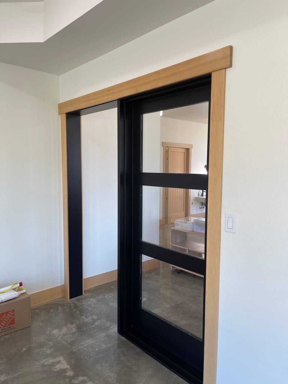 Black-framed sliding barn door in a white room with a wooden header trim.