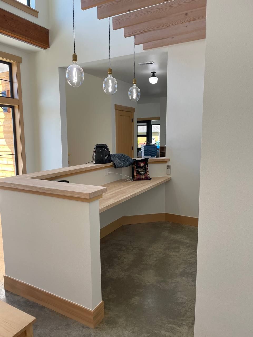 Modern office lobby with wood ceiling, pendant lights, and a curved reception counter
