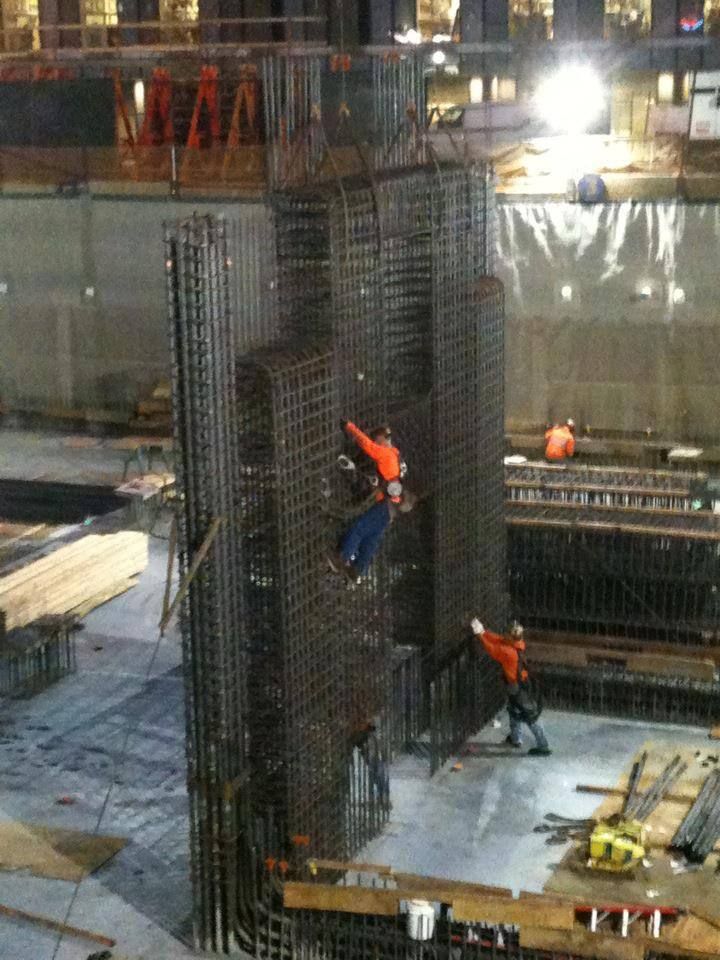 Construction workers on a rebar column framework at a building site at night