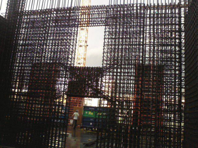 Construction site with a tall rebar frame and a yellow crane in the background
