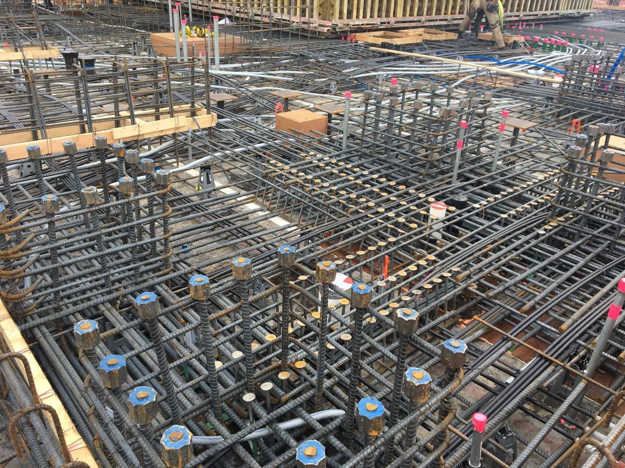 Rebar grid and concrete foundation under construction with steel columns and scattered pink markers