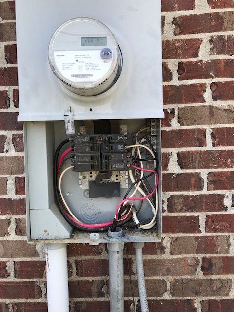 A brick wall with a meter and wires attached to it