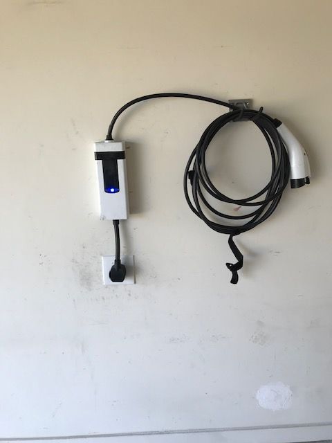 An electric car charger is attached to a wall