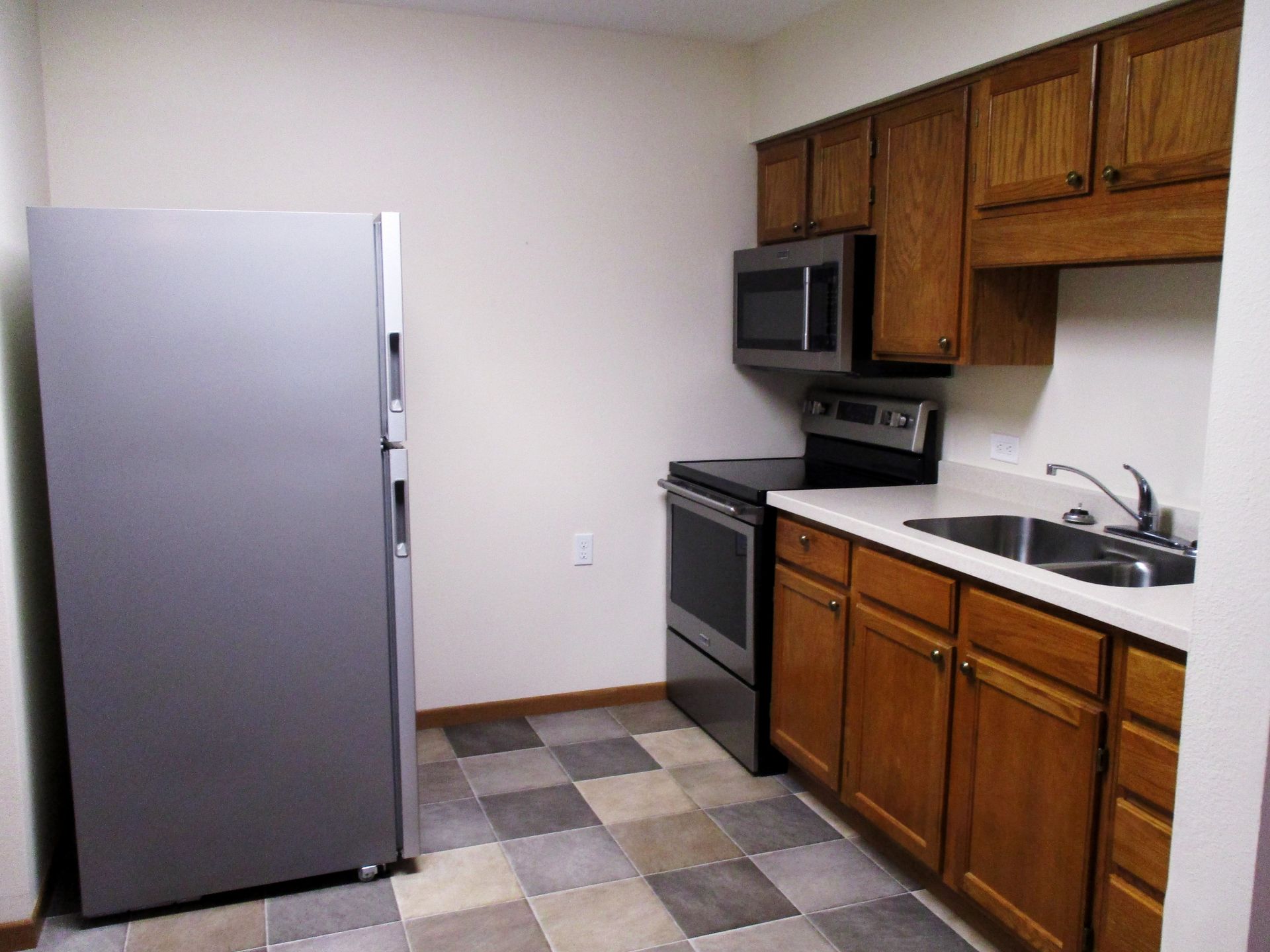 A kitchen with wooden cabinets and a silver refrigerator