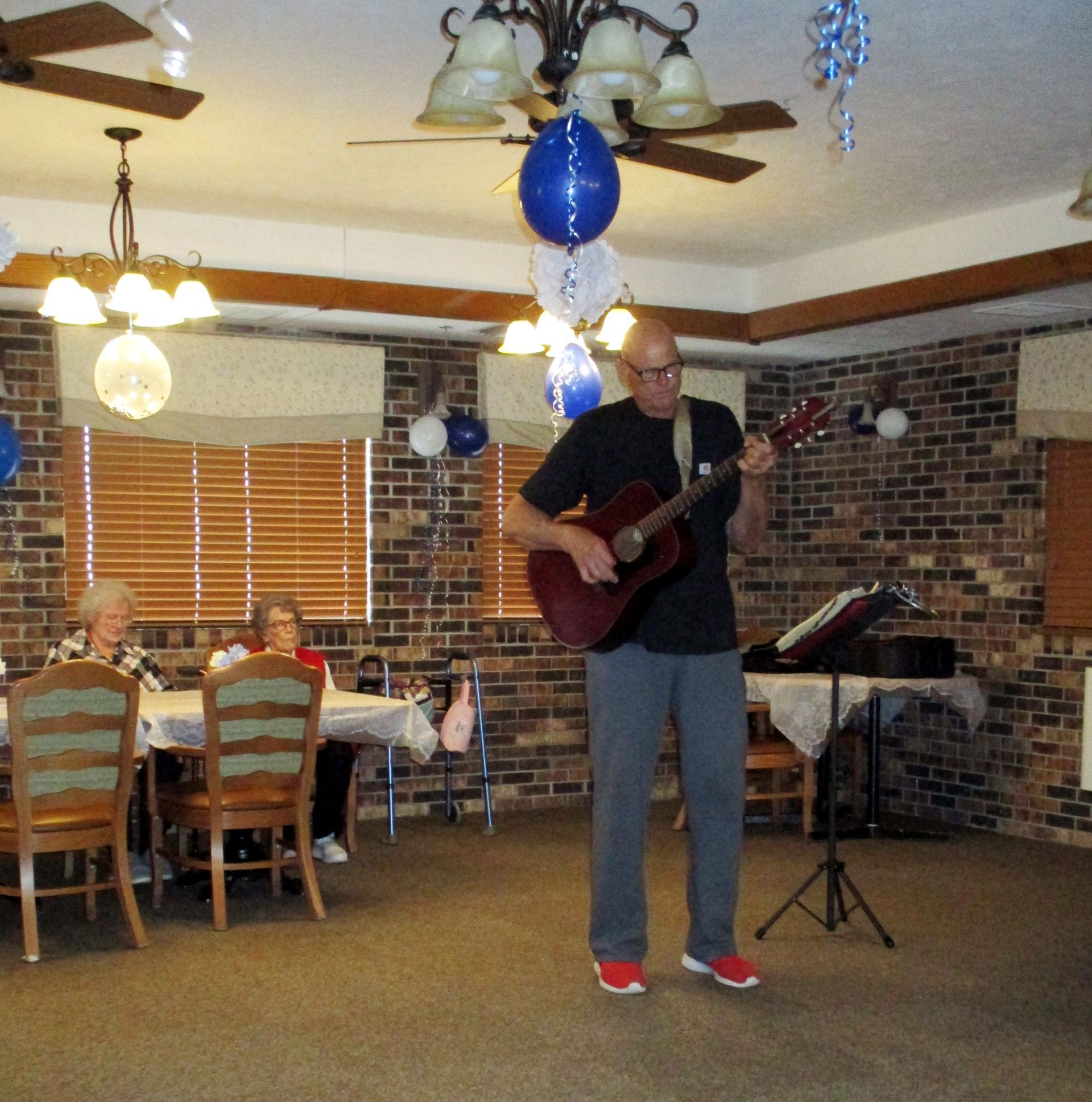 A man playing a guitar in a room with tables and chairs