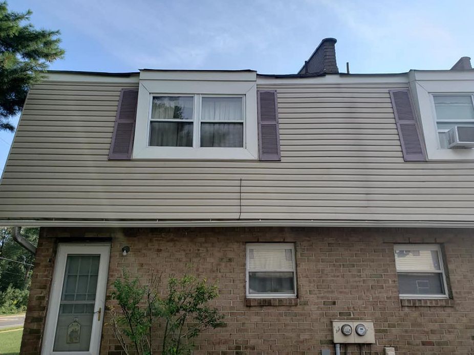 A brick house with a roof that has a chimney on it.