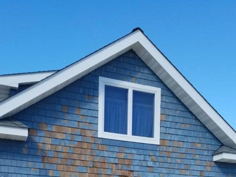 A blue house with a white window on the roof