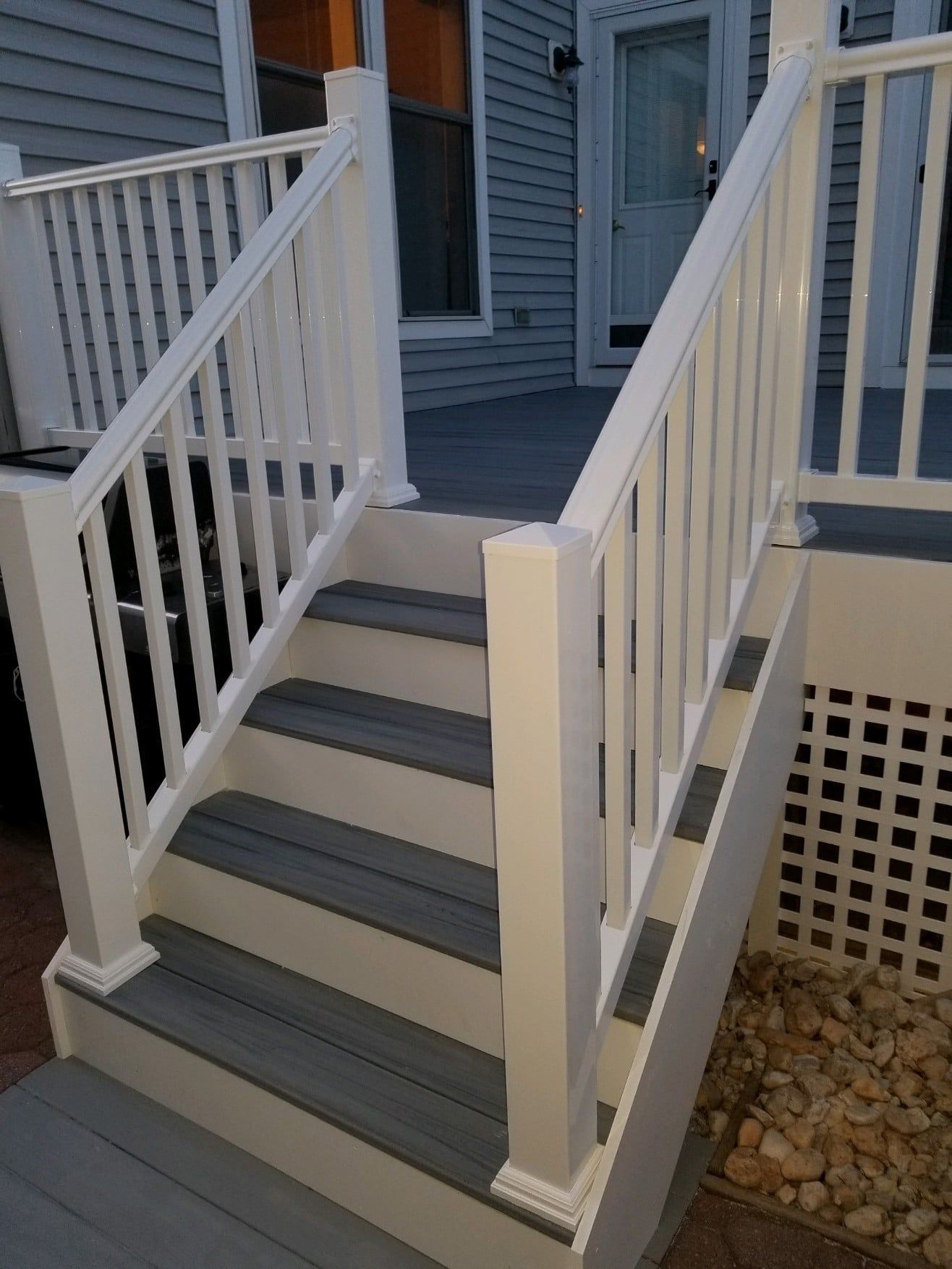 A set of stairs leading up to a porch with a white railing.