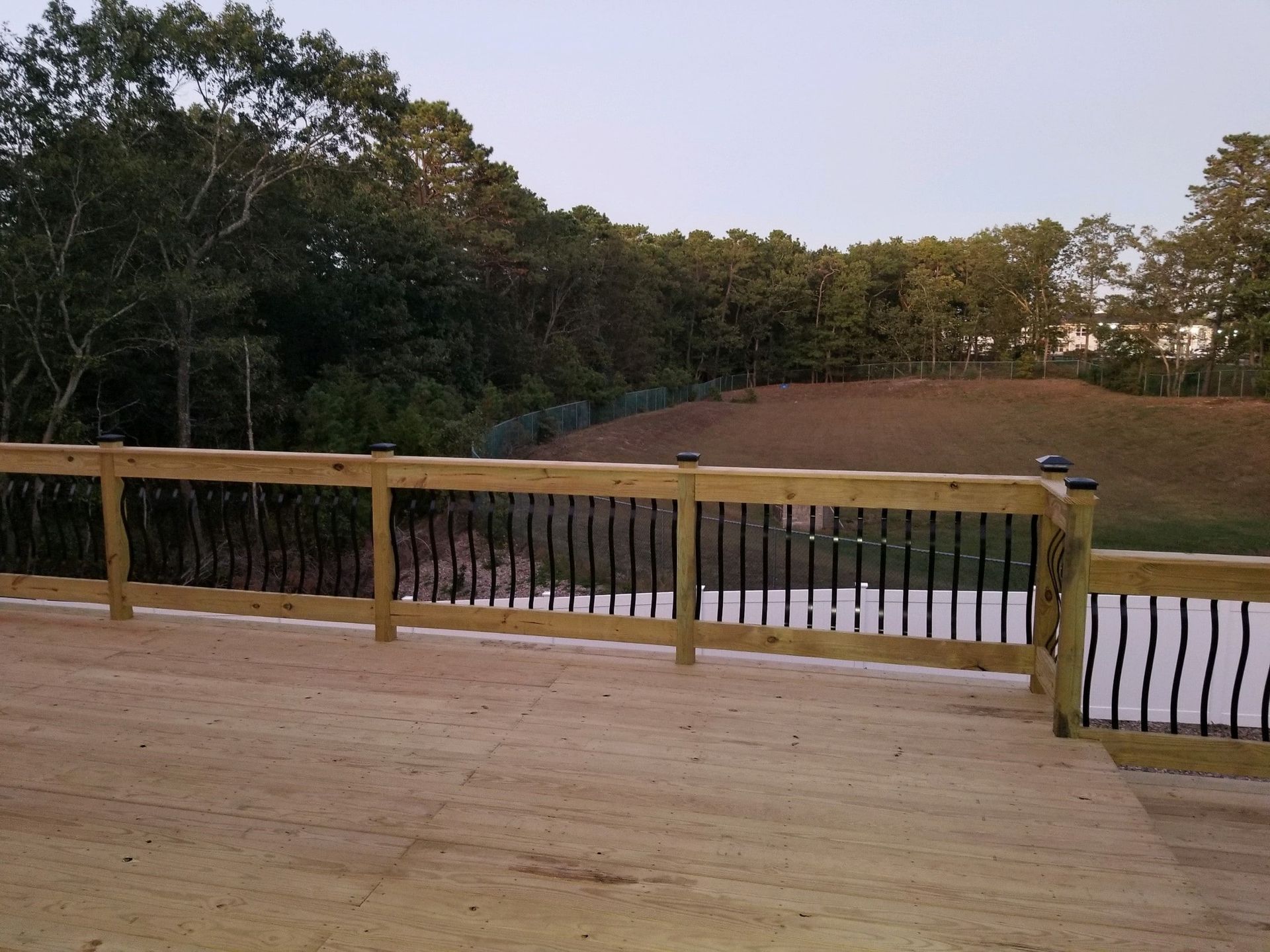 A wooden deck overlooking a lake with trees in the background