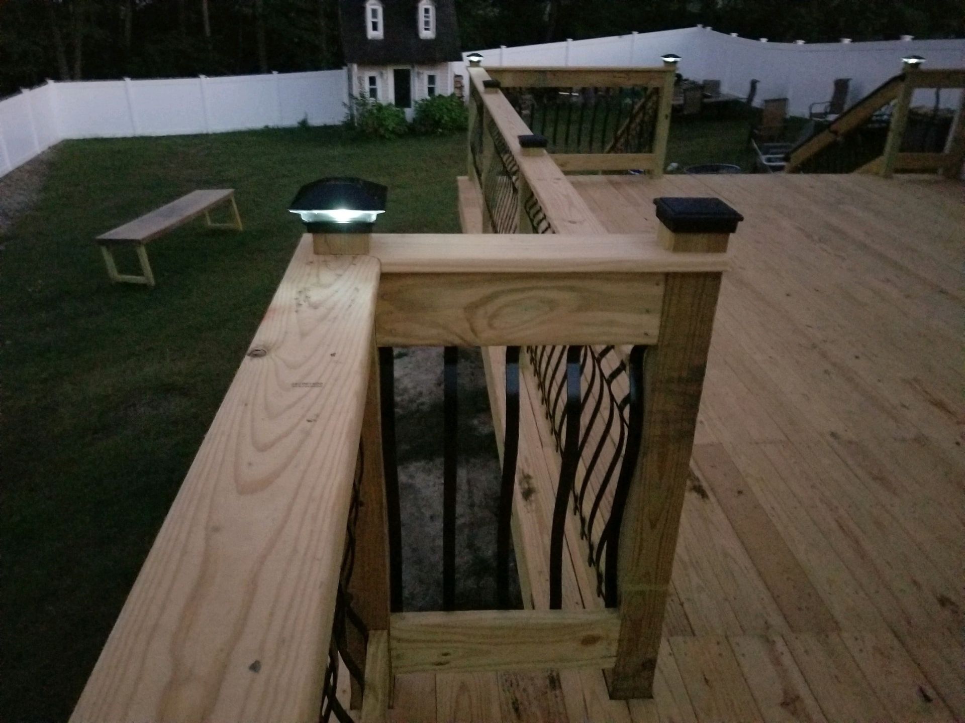 A wooden deck with a white fence in the background