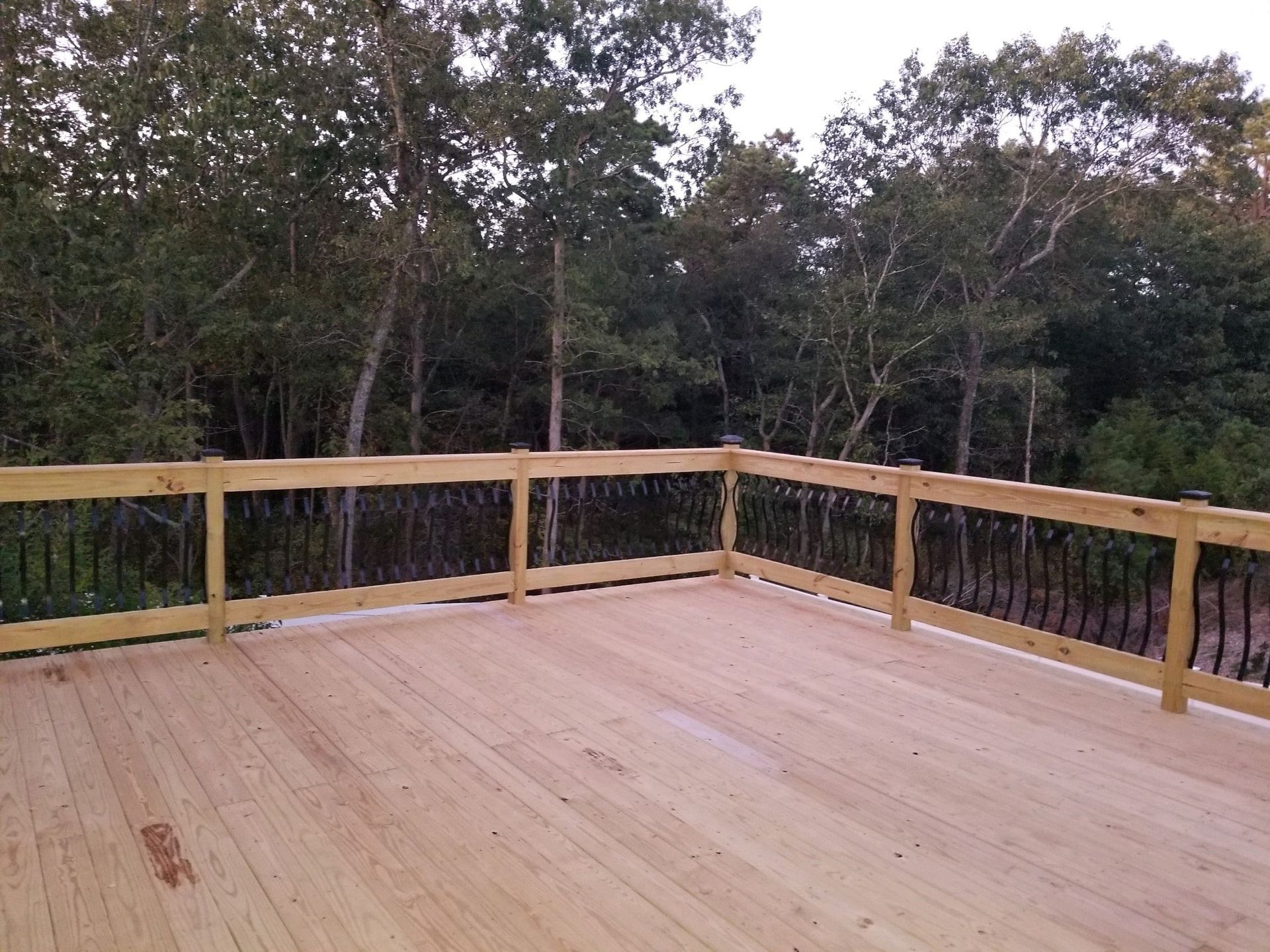 A wooden deck with a railing and trees in the background