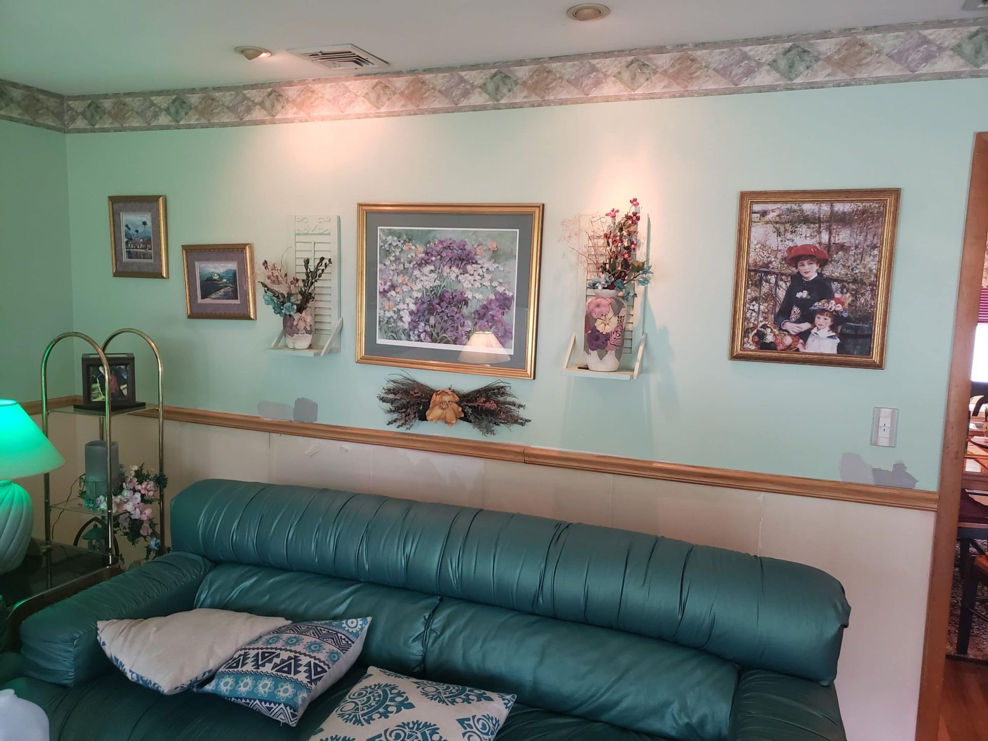A living room with a green couch and pictures on the wall
