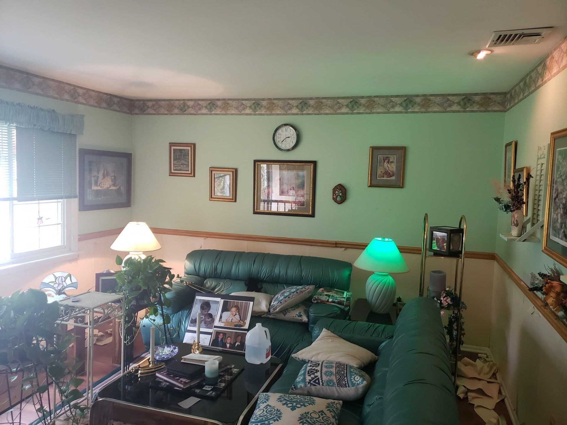 A living room with a couch , coffee table , lamps and pictures on the wall.