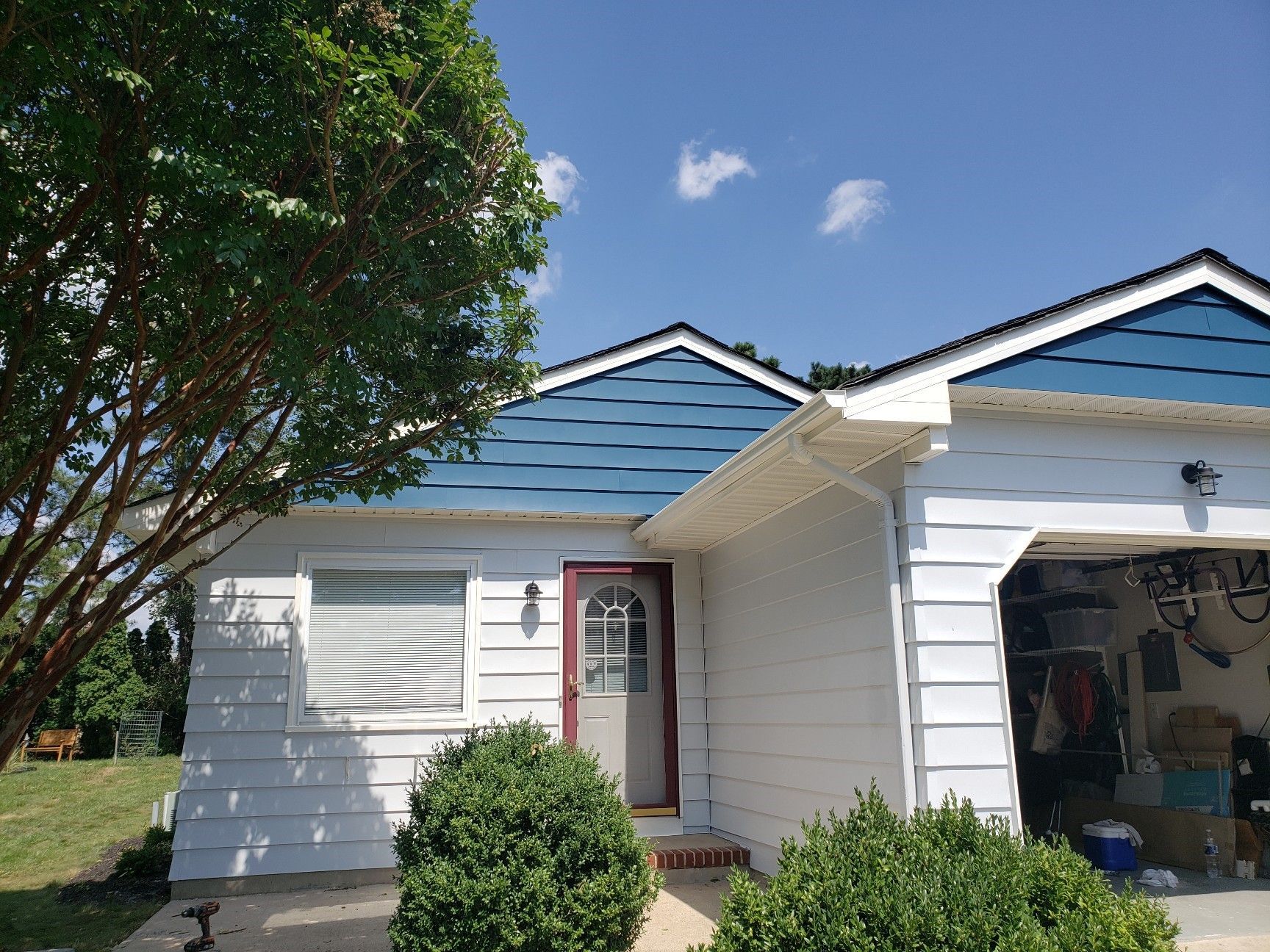 A white house with a blue roof and a garage.