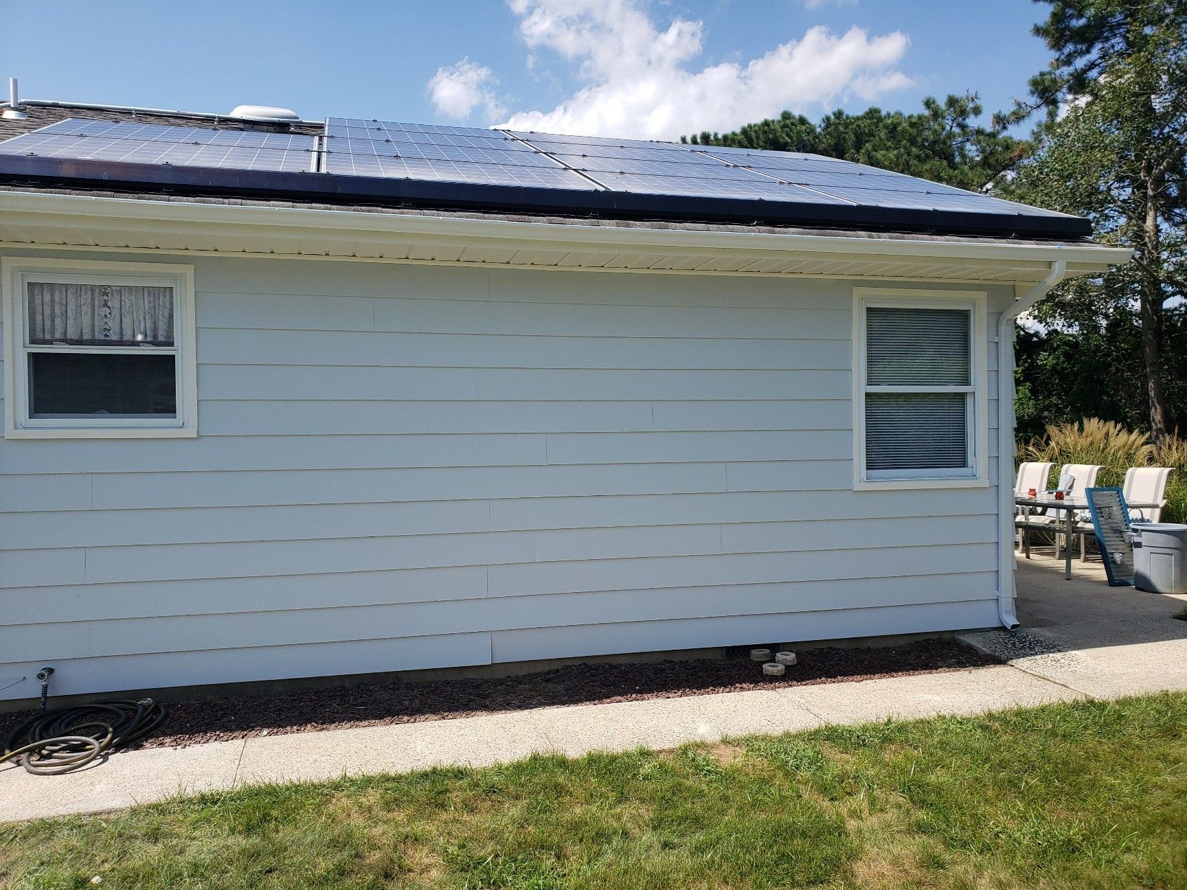 A white house with a solar panel on the roof.