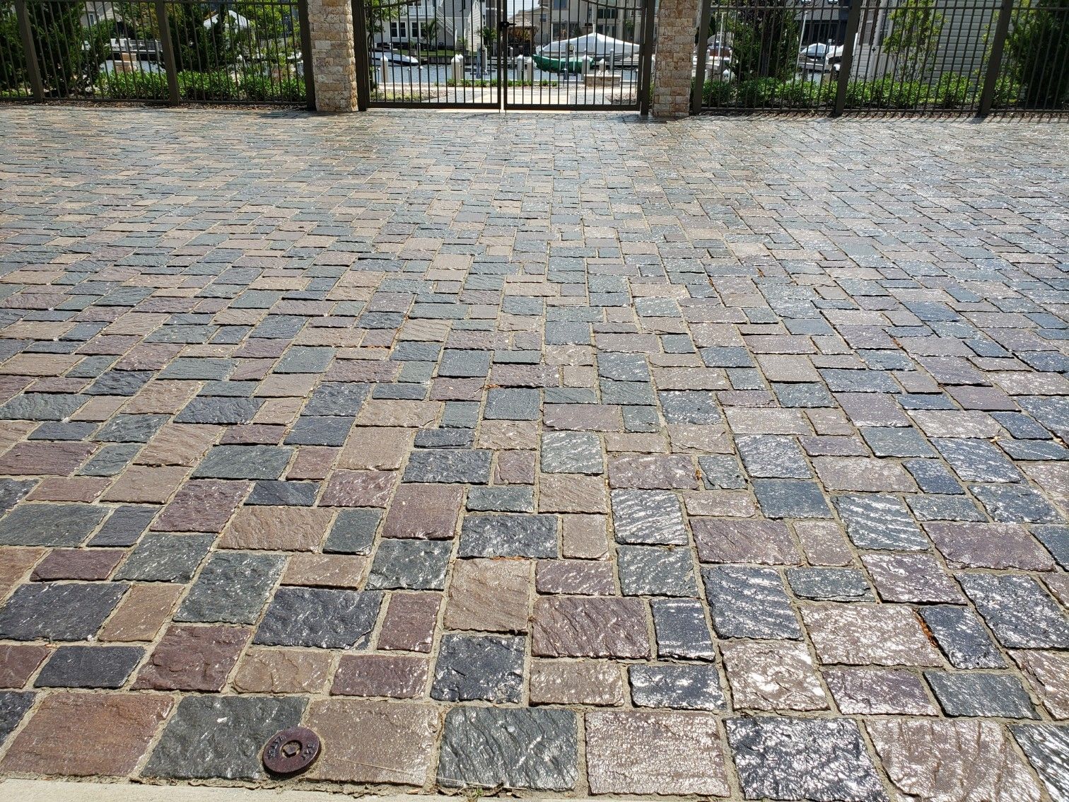 A cobblestone driveway with a gate in the background.