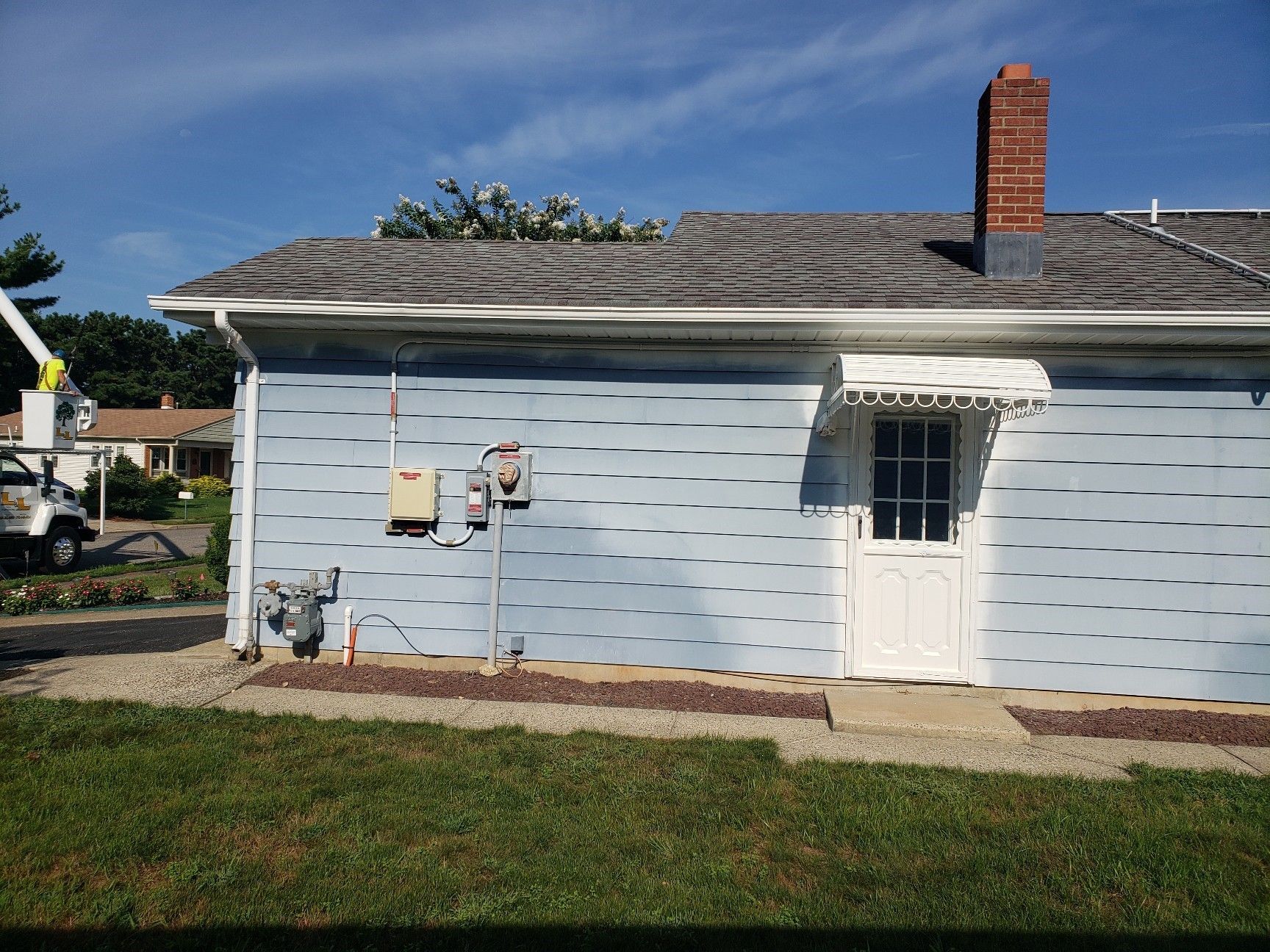 A blue house with a white door and a chimney on the roof.