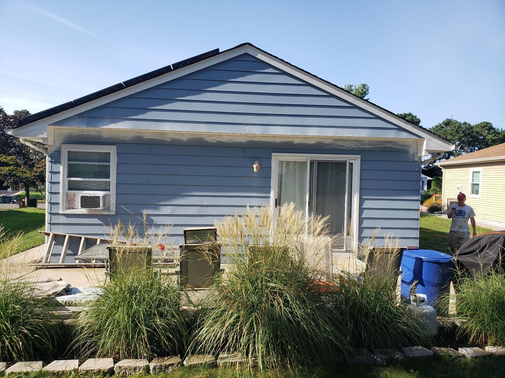 A man is standing in front of a blue house.