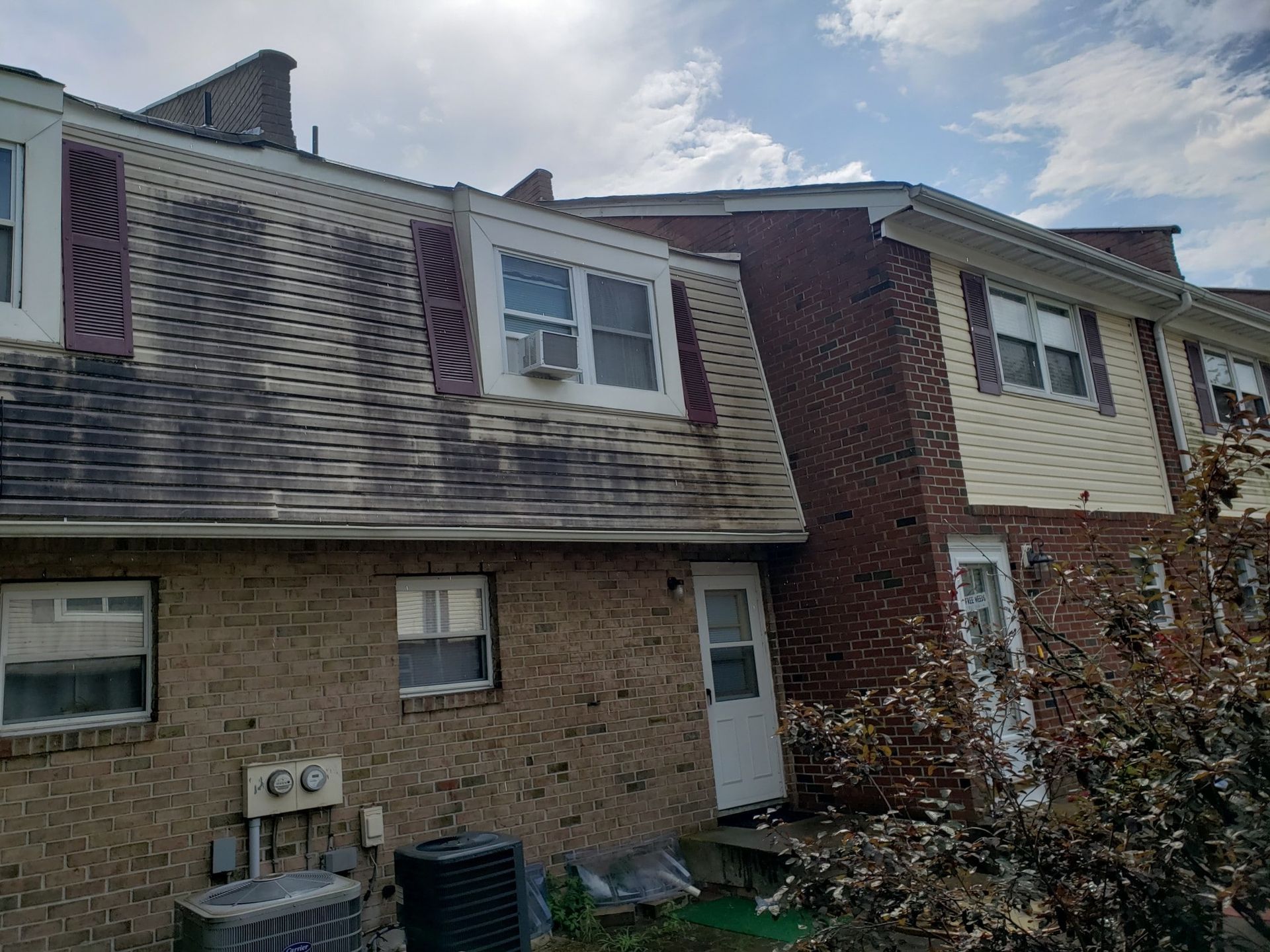 A brick house with a roof that has been damaged by a storm.