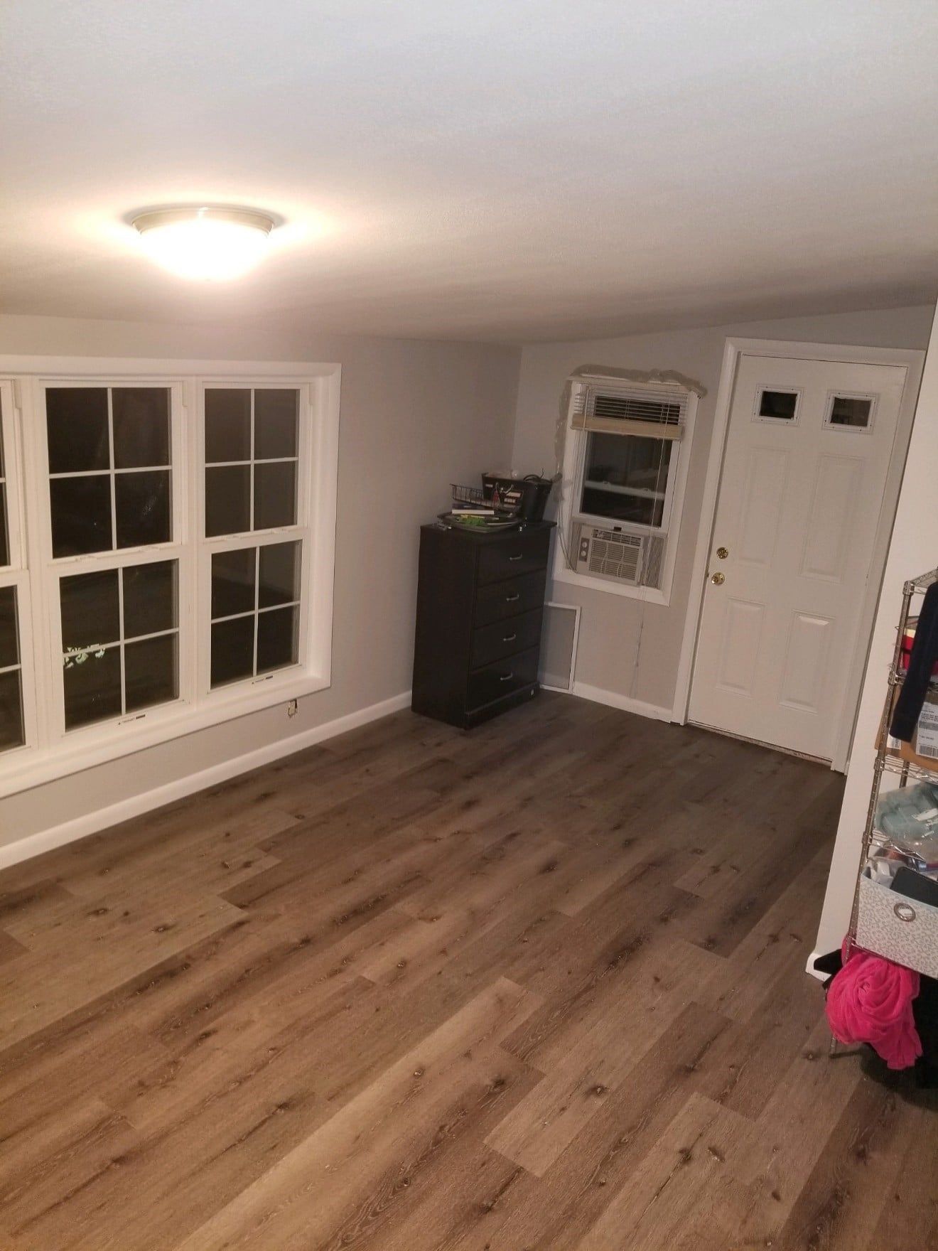 A living room with hardwood floors and two windows.