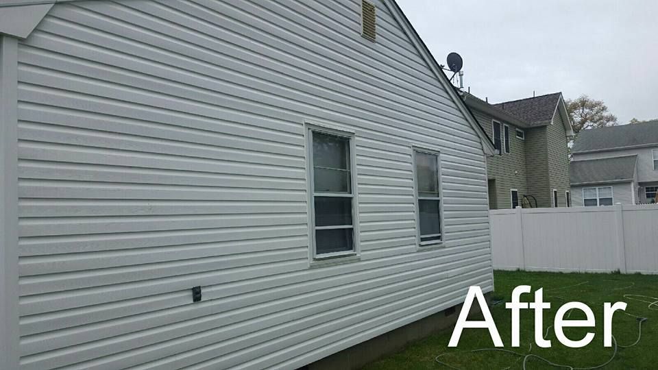 A picture of a house after being cleaned with a white fence in the background.