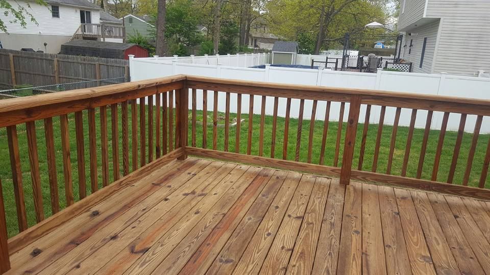 A wooden deck with a white fence in the backyard.