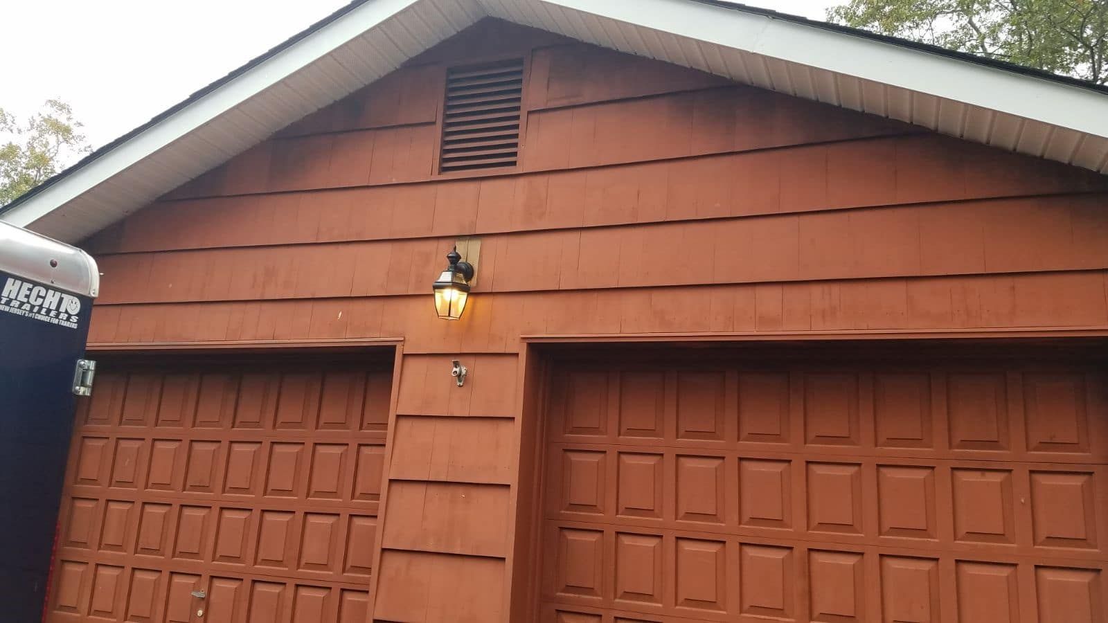 A garage with a blue trailer parked in front of it.