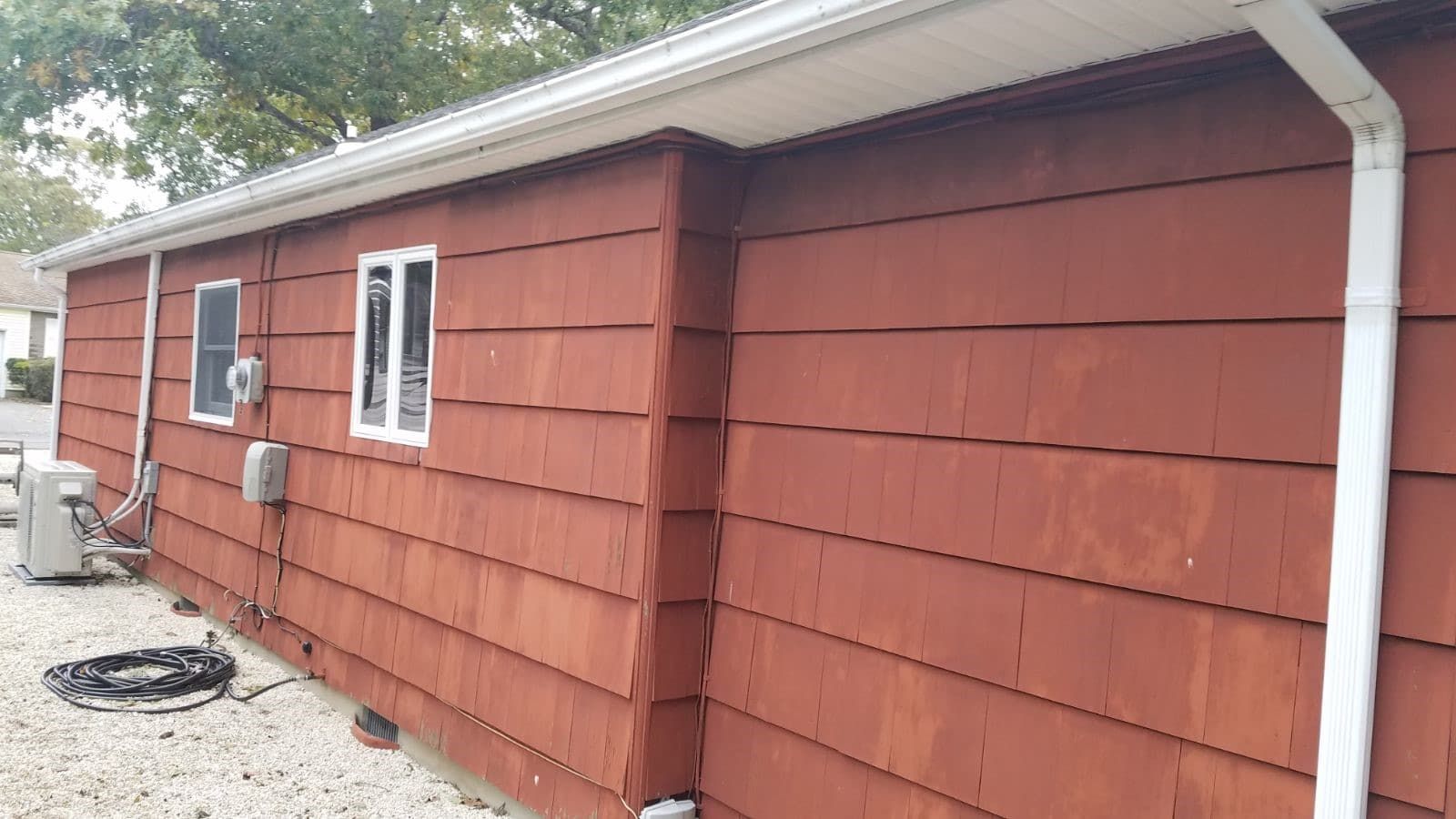 The side of a red house with a white gutter and windows.