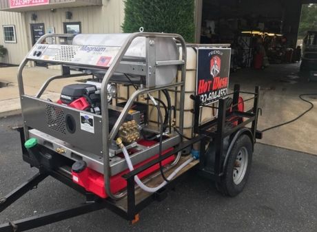An orange and black pressure washer with wheels on a white background